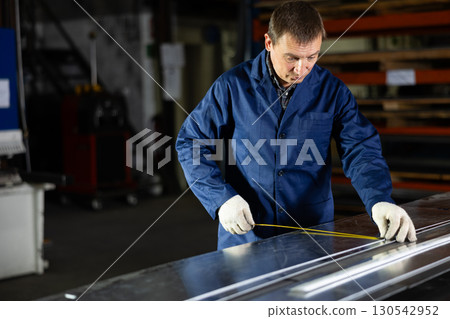 Worker applying markings on steel sheet in metal workshop Worker applying markings on steel sheet in metal workshop 130542952