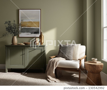 Cozy living room corner with white armchair, wooden side table, and green cabinet decorated with vases and artwork, bathed in natural sunlight 130542992