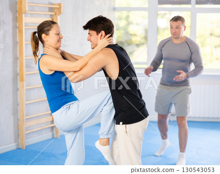 Guy and woman train to perform defense of strangling opponent, while learning self-defense 130543053