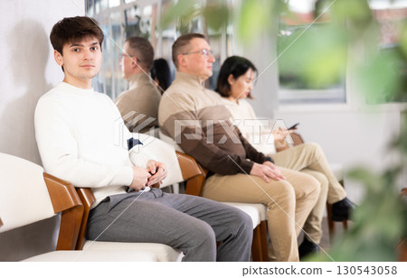 Young guy sits in line at reception 130543058