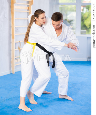 Coach teaches young woman techniques for wrestling and throwing on sports mats during judo training 130543098