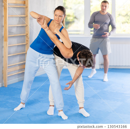 Guy and woman train of performing protection with wring hands during training in self-defense Guy and woman train of performing protection with wring hands during training in self-defense 130543166