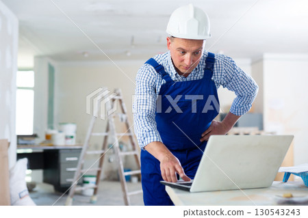 Man builder using laptop in construction site Man builder using laptop in construction site 130543243
