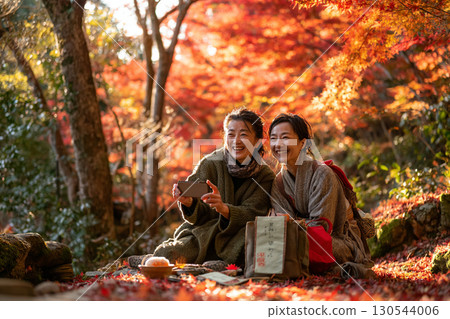 A woman taking photographs of autumn leaves 130544006