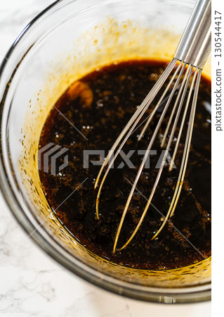 A top-down view of dark molasses and two eggs in a glass bowl, part of the wet ingredients for Zesty Orange Gingerbread Cookie Dough. The molasses adds depth and a rich color to the gingerbread. A top-down view of dark molasses and two eggs in a glass bowl, part of the wet ingredients for Zesty Orange Gingerbread Cookie Dough. The molasses adds depth and a rich color to the gingerbread. 130544417