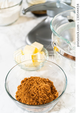 Side view of brown sugar and butter in separate glass bowls, ready to be creamed together as part of the Classic Gingerbread Cookie Dough recipe. These ingredients create a sweet, rich base for the Side view of brown sugar and butter in separate glass bowls, ready to be creamed together as part of the Classic Gingerbread Cookie Dough recipe. These ingredients create a sweet, rich base for the 130544434