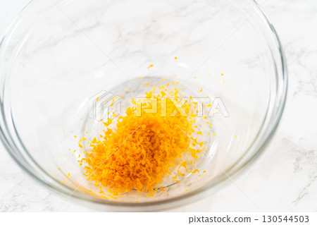A closeup of bright orange zest in a glass bowl, which will add a zesty flavor to the Zesty Orange Gingerbread Cookie Dough. This fresh zest is key to enhancing the dough citrusy undertone. A closeup of bright orange zest in a glass bowl, which will add a zesty flavor to the Zesty Orange Gingerbread Cookie Dough. This fresh zest is key to enhancing the dough citrusy undertone. 130544503