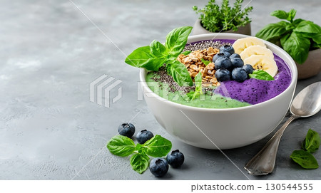 Colorful smoothie bowl topped with fresh fruits and granola on a light grey background 130544555