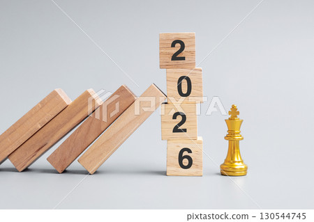 wooden Dominoes falling against 2026 stop blocks with golden Chess King figure. Business, Risk Management, Solution, economic, Insurance and New Year concept wooden Dominoes falling against 2026 stop blocks with golden Chess King figure. Business, Risk Management, Solution, economic, Insurance and New Year concept 130544745
