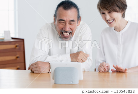 一對老年夫婦在客廳與智慧音箱交談 130545828