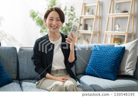 使用智能手機的婦女在客廳 使用智能手機的婦女在客廳 130546195