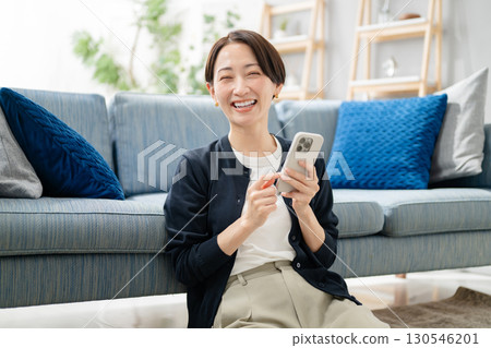 A woman using a smartphone in the living room A woman using a smartphone in the living room 130546201