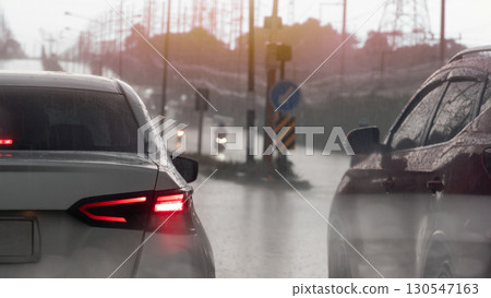 Rear side of white car stop on the road with in rainy time. Rain fell on the car causing water droplets to splash all over the area. Blurred of cars and motorcycles driving through the rain at day. Rear side of white car stop on the road with in rainy time. Rain fell on the car causing water droplets to splash all over the area. Blurred of cars and motorcycles driving through the rain at day. 130547163
