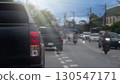 Rear side of pickup car black color. Car parking side of asphalt road. Other cars and motorcycle driving in the city at day time. 130547171