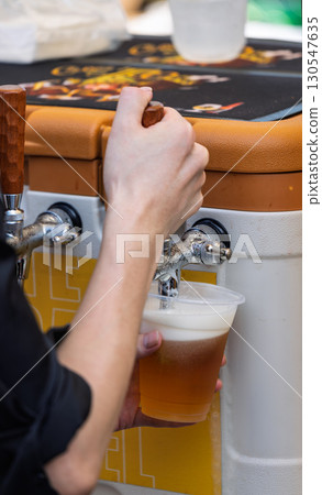 從啤酒桶向塑膠杯倒入生啤酒 130547635