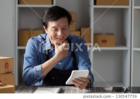 Smiling warehouse manager reviewing inventory on a tablet for efficient operations. Smiling warehouse manager reviewing inventory on a tablet for efficient operations. 130547739