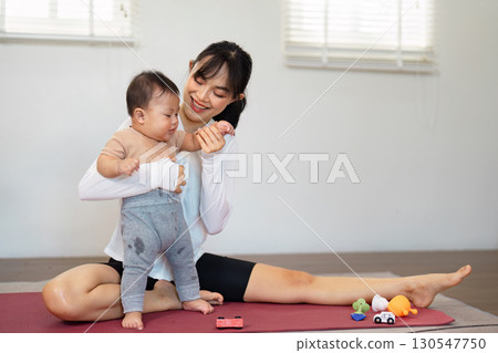 Joyful Asian mother exercising with her toddler, promoting wellness and active parenting in a playful home environment. Joyful Asian mother exercising with her toddler, promoting wellness and active parenting in a playful home environment. 130547750