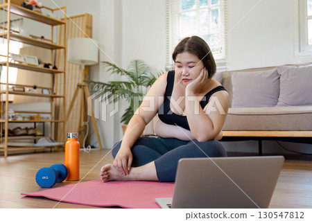 Thoughtful woman resting after workout with dumbbells at home. 130547812