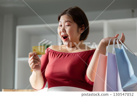 Excited woman shopping with credit card and colorful bags Excited woman shopping with credit card and colorful bags 130547852