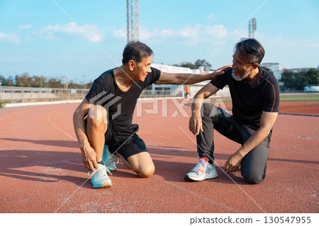 Supportive elderly men encouraging each other after a workout on a track. Highlighting friendship, wellness, and active aging. 130547955