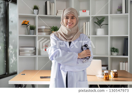 Confident Muslim female doctor posing with stethoscope in a modern healthcare office, showcasing diversity and professionalism. Confident Muslim female doctor posing with stethoscope in a modern healthcare office, showcasing diversity and professionalism. 130547973