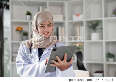 Engaged Muslim female doctor using a tablet to review patient information in a modern healthcare office, emphasizing technology and diversity. Engaged Muslim female doctor using a tablet to review patient information in a modern healthcare office, emphasizing technology and diversity. 130547981