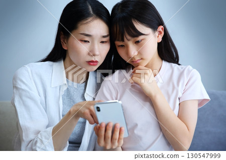 一位母親和女兒認真地看著智慧型手機的圖片 一位母親和女兒認真地看著智慧型手機的圖片 130547999
