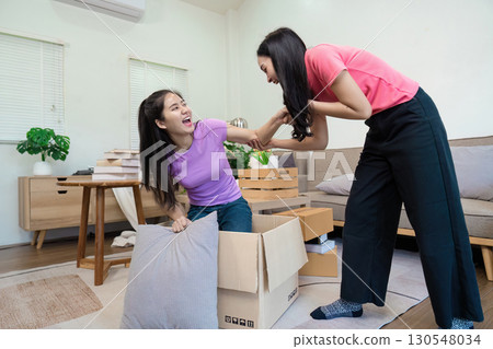 Joyful LGBTQ couple unpacking boxes and celebrating their new home together in a cozy living room. Joyful LGBTQ couple unpacking boxes and celebrating their new home together in a cozy living room. 130548034