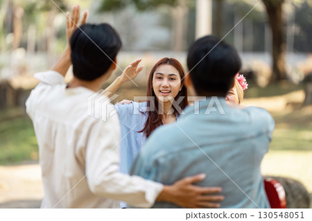 Friends warmly greeting each other during a fun picnic gathering in the park. 130548051