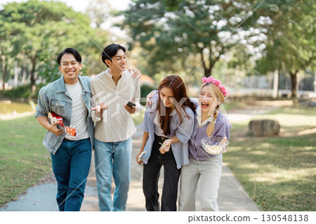 Diverse group of friends laughing and walking together in a park. Diverse group of friends laughing and walking together in a park. 130548138