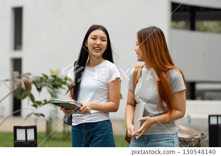 Diverse university students walking and laughing together on campus. Diverse university students walking and laughing together on campus. 130548140