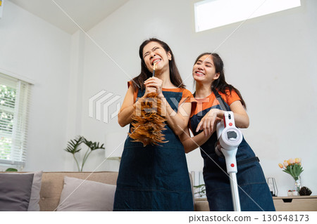 Housekeeping service with two women joyfully cleaning with a duster and vacuum. Housekeeping service with two women joyfully cleaning with a duster and vacuum. 130548173