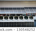 solar panels in a factory, Industrial cooling tower fans installed beneath solar panels on factory rooftop, representing sustainable technology, clean energy integration, ventilation system 130548252