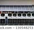 solar panels in a factory, Industrial cooling tower fans installed beneath solar panels on factory rooftop, representing sustainable technology, clean energy integration, ventilation system 130548253