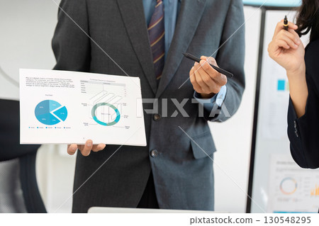 Businessman holding financial report with graphs during a presentation. Businessman holding financial report with graphs during a presentation. 130548295