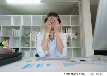 Stress and Fatigue. Young woman feeling overwhelmed at work, covering her face with hands. Stress and Fatigue. Young woman feeling overwhelmed at work, covering her face with hands. 130548373