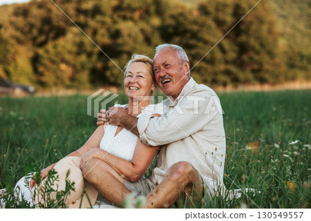 Happy senior couple embracing in meadow at sunset. 130549557