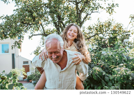 Grandfather playing with granddaughter in the garden. 130549622
