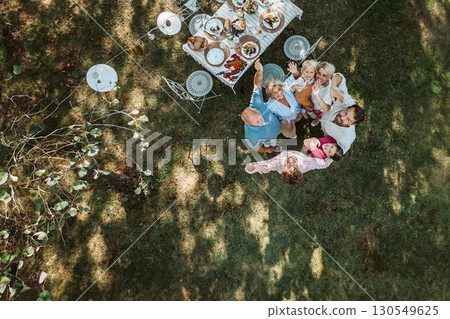Drone shot of grandparents, parents and children hugging in circle at family celebration 130549625