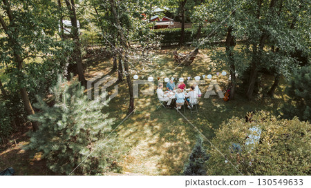 Areal view of grandparents, parents and kids dining together outside. 130549633