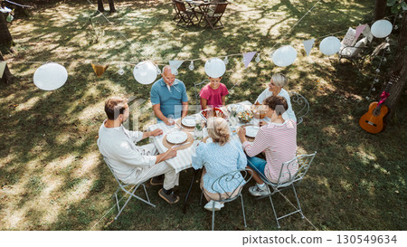 Areal view of grandparents, parents and kids dining together outside. 130549634