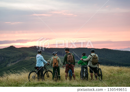 Family standing with bicycles at sunset in mountains. Cycling trip during autumn day. 130549651