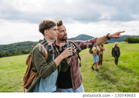 Father showig somenting in distance to son during hiking trip. Father showig somenting in distance to son during hiking trip. 130549683