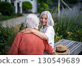 Elderly mother sitting on bench with adult daughter. 130549689