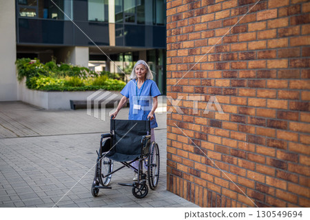 Nurse in uniform pushing empty wheelchair. Nurse in uniform pushing empty wheelchair. 130549694