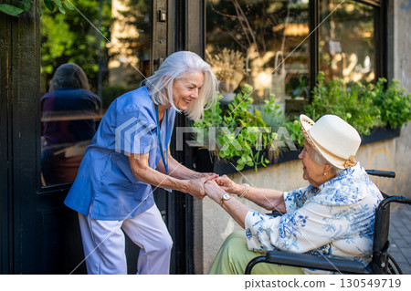Tender moment between older caregiver and senior female patient in wheelchair. 130549719