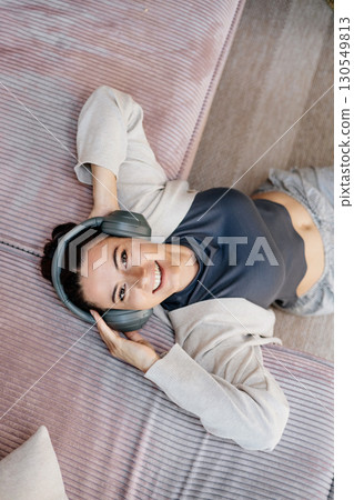 Woman relaxing at home, enjoying music after work. Woman relaxing at home, enjoying music after work. 130549813