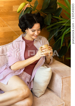 Portrait of woman with hair rollers during slow morning. 130549893