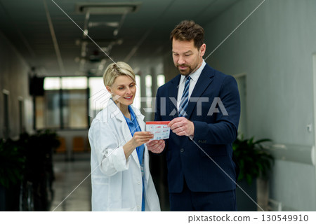 Pharmaceutical sales representative introducing new medication to female doctor. 130549910