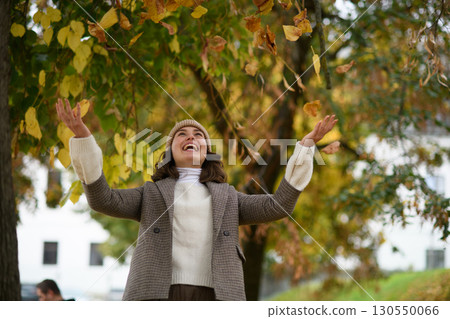 Happy woman throwing fallen autumn leaves into air. Happy woman throwing fallen autumn leaves into air. 130550066